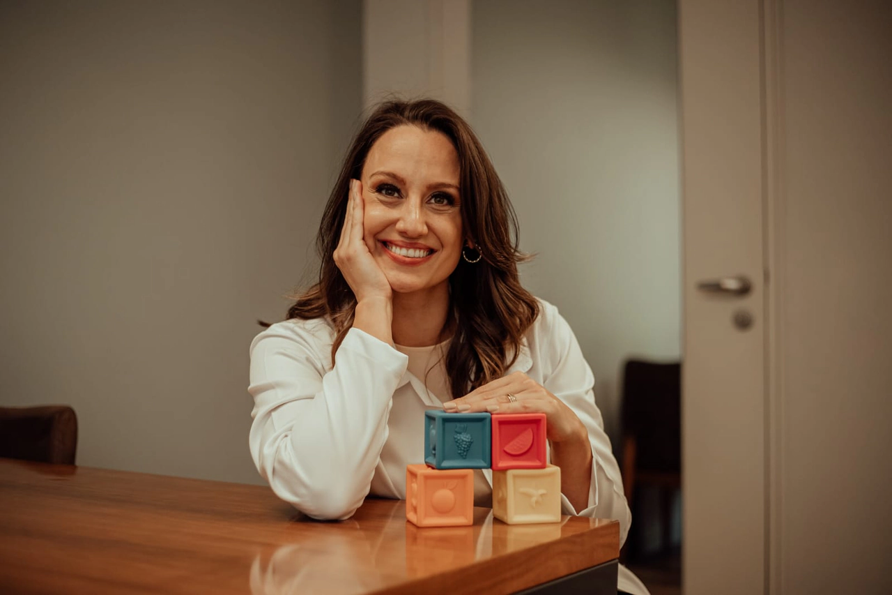 Dra. Leticia Januario durante atendimento pediatrico com expressao acolhedora.